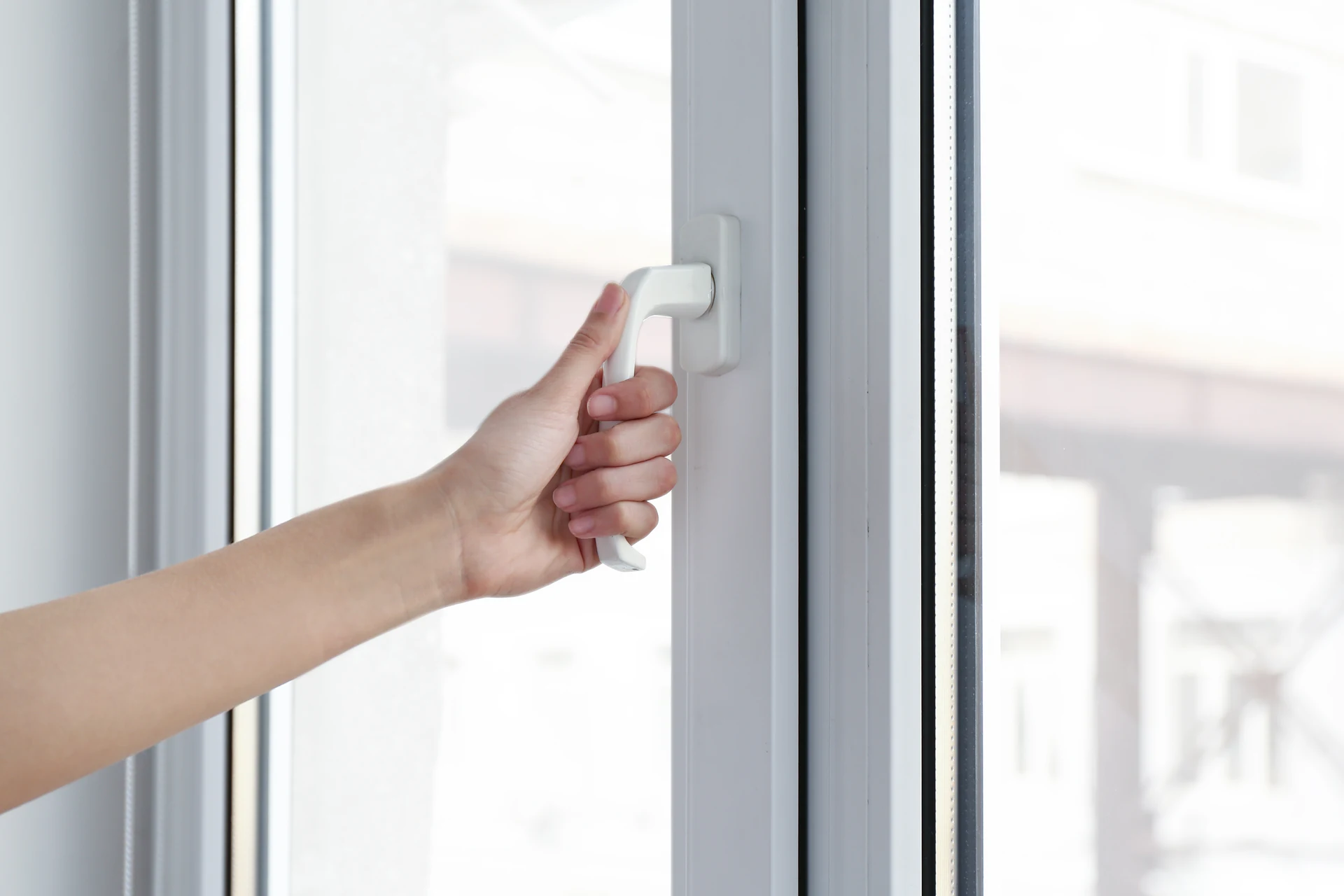 Hand opening a white uPVC tilt and turn window in Neath