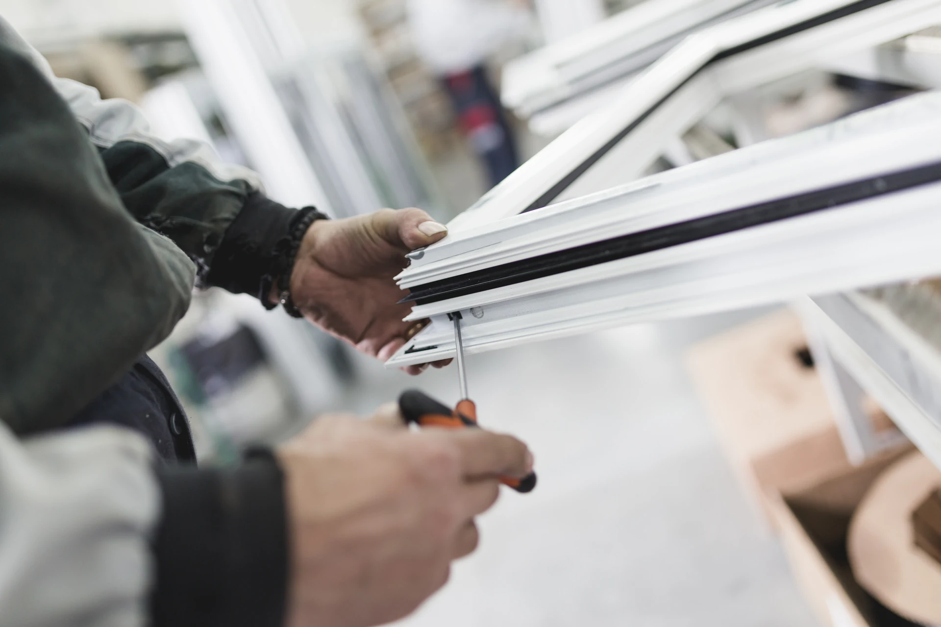 Installer assembling a white uPVC window frame in the workshop, Port Talbot