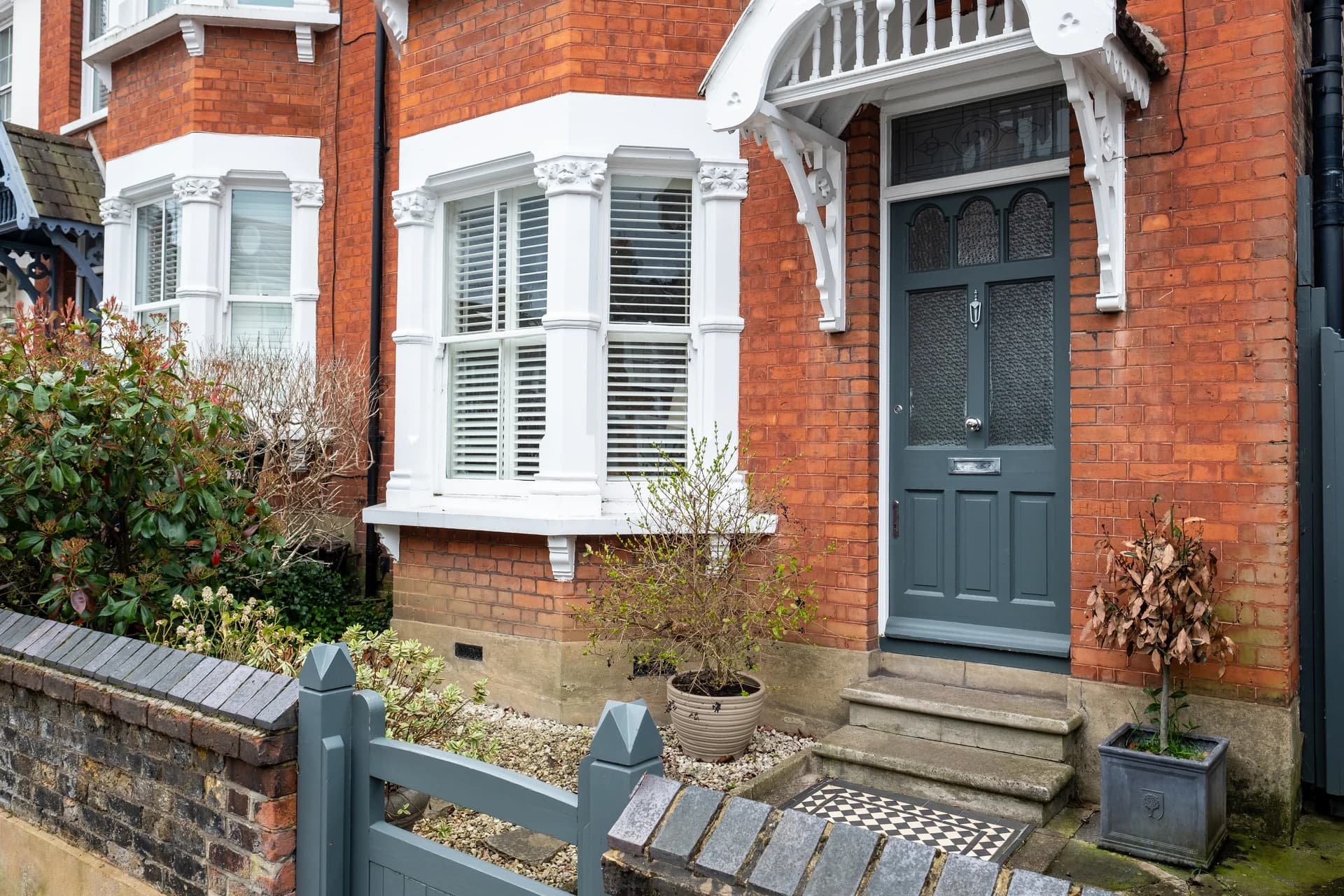 Red-brick Victorian home in Neath with a white uPVC bay window and grey composite front door fitted by Bully Windows